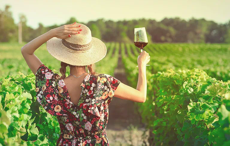 Kobieta w kapeluszu z lapmką wina w dłoni